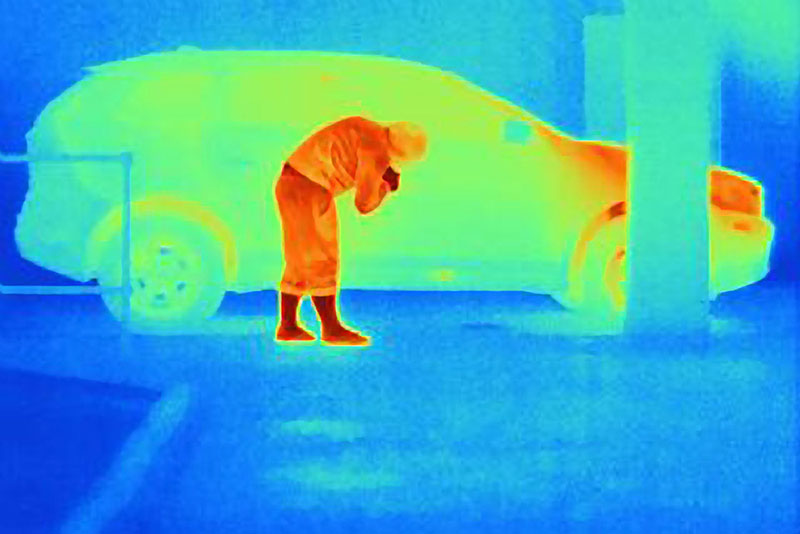 Someone tampering a car and it being shown in infrared