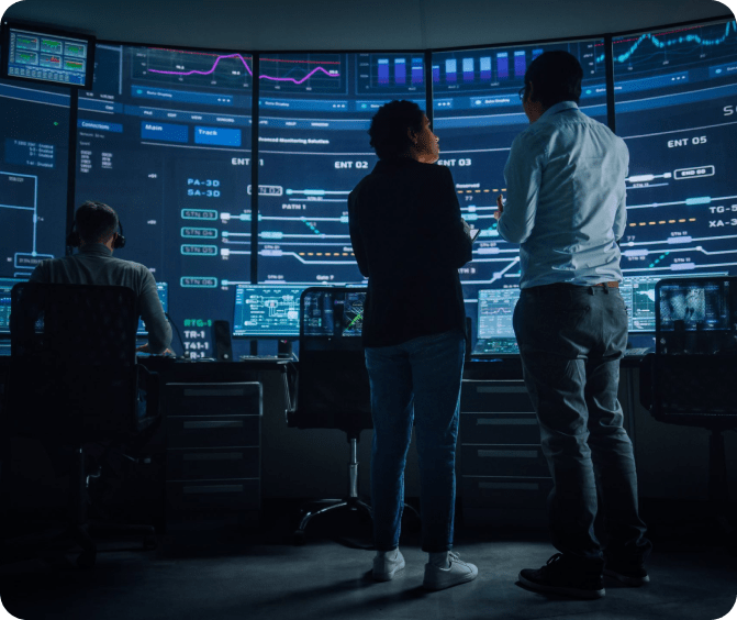 A picture of a few people looking at a video wall in a command center